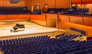 A photo taken from the top of the stalls left hand stair case looking over the empty auditorium and piano sat alone onstage