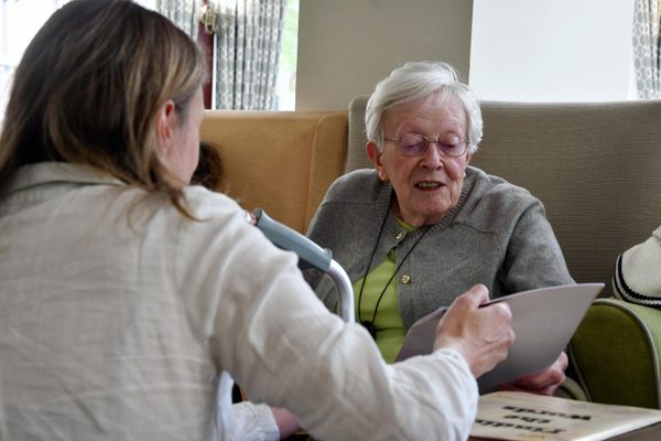 A young woman in a white shirt showing a booklet to an older woman