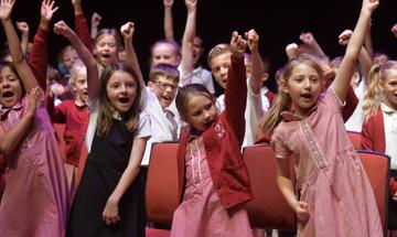 school children singing on stage