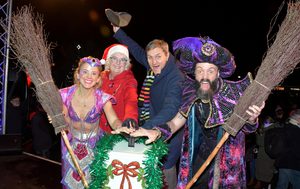 Spirit of the Ring and Abanazer stand either side of the Tadley Parish Chairman and Kit Malthouse MP. All four of them hold their hands over the large button ready to turn on the lights
