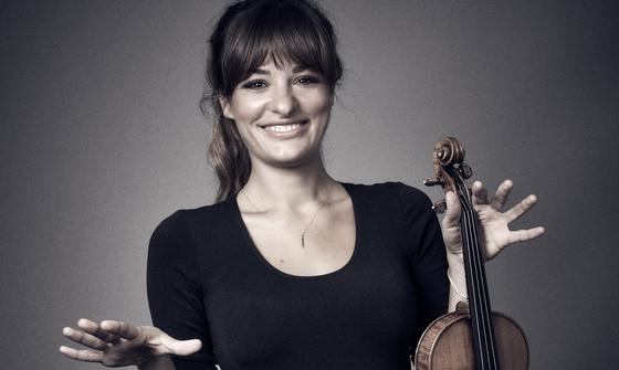 Nicola Bendetti smiling whilst holding her violin.