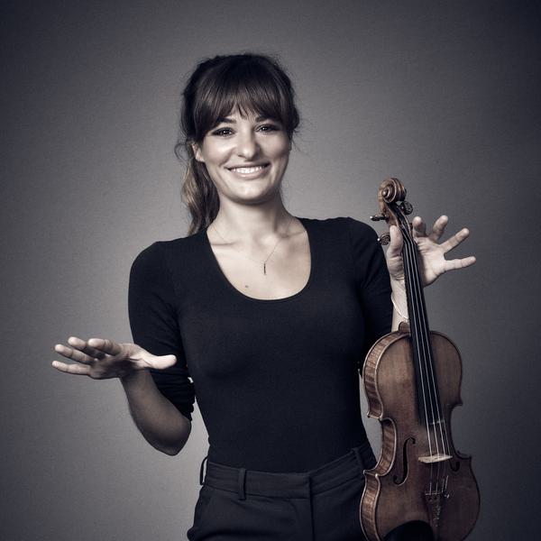 Nicola Bendetti smiling whilst holding her violin.