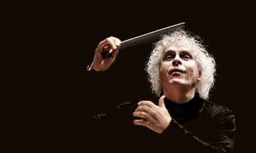 Sir Simon Rattle shown against a dark background, baton is in motion as he conducts