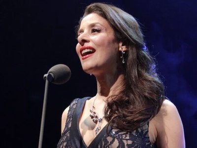 An image of female singer, Poppy Tierney, singing on stage in a black dress