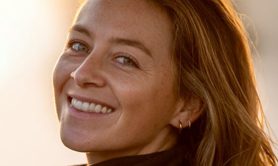 A white woman with dark blonde hair in a black fleece smiling over her shoulder