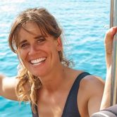 A white woman with dark blonde hair smiling while stood on a boat