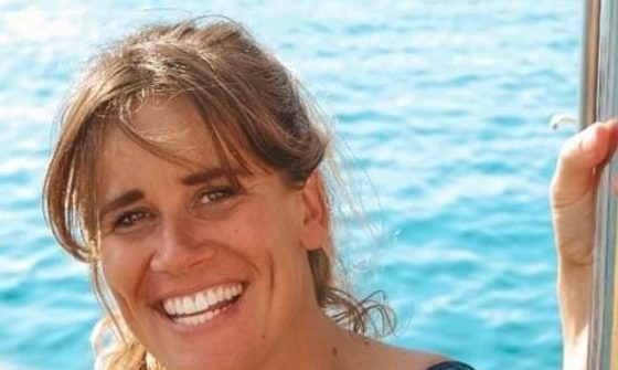 A white woman with dark blonde hair smiling while stood on a boat