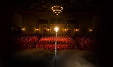 A dark auditorium with a ghost light over the seats