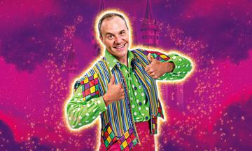 Panto comic Chris Pizzey wearing a brightly coloured outfit giving the thumbs up against a purple sparkly background with a castle