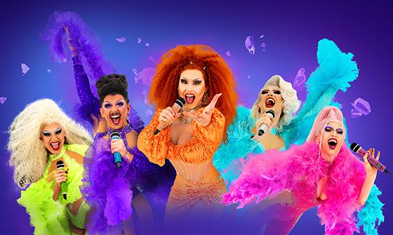 Five drag queens each dressed in neon clothes and feather boas, singing into microphones and looking at the camera