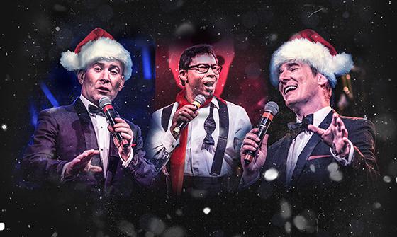Three members of The Rat Pack singing into microphones. Two of the men on either side are wearing Santa hats