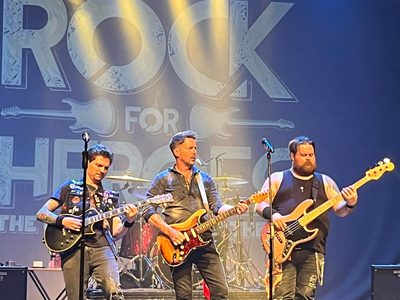 Three men performing with guitars on stage
