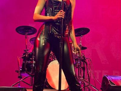A woman in a leather outfit singing into a microphone