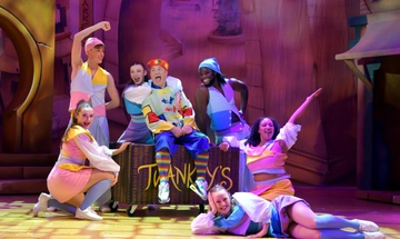 Wishee Washee sits on a laundry basket surrounded by the ensemble