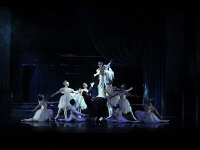 a group of dancers, most on the floor looking up to a male dancer