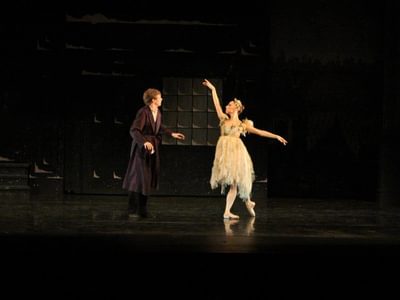 two dancers, a man and a woman. The man is watching the woman