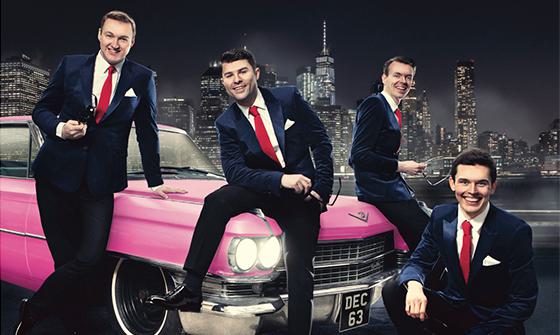 Four men in black suits with white shirts and red ties sat on a pink car with a black and white city skyline behind them