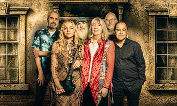 Six members of Steeleye Span posing against a textured wall with vintage-style windows