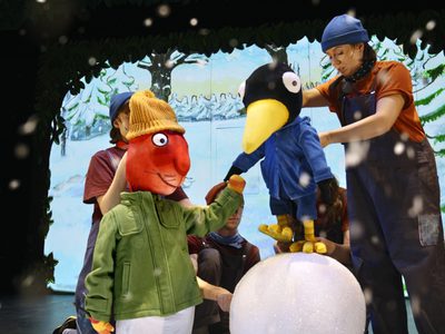 Squirrel and Bird are in coats and hats rolling a big snowball to build a snowman