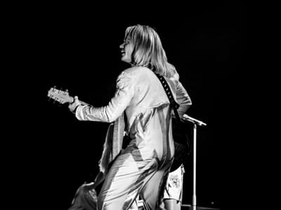 A black and white image of a Björn performer with his back to the camera playing the guitar