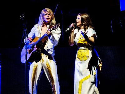 A Björn and Anni-Frid performer playing guitar and singing together