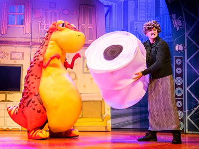 A man passes a giant roll of toilet paper to Dino