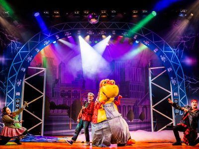 Danny and Dino stand back to back in the centre of the stage with two performers kneeling down and pointing at them from either side