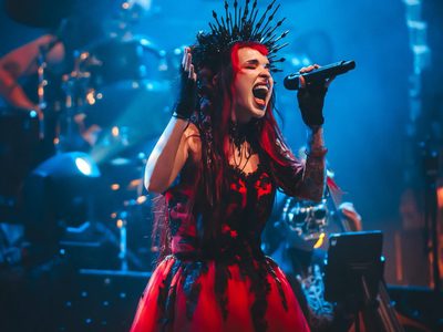 a woman wearing red and black singing on stage