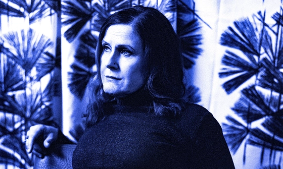 A photo of Alison Moyet in a turtleneck jumper with floral curtains behind. the whole image has a blue hue