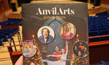 A photo of the autumn brochure in The Anvil Auditorium, the cover has ballerinas, panto cast, Tom Stade, Lucy Worsley, and Les Amazones d'Afrique