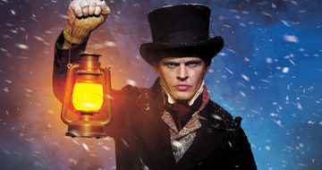 A grumpy white man in a top hat, shirt, cravat, waist cost, duffle coat, and fingerless gloves holding a lantern in the middle of snow