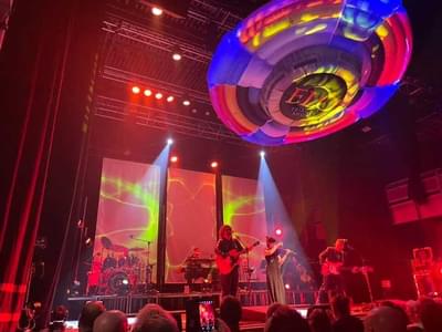 The ELO Tribute Show performing on stage bathed in red light. There is a large inflatable spaceship above them