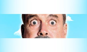 A close up of John Cleese wide eyes and nose on a blue sky background with clouds