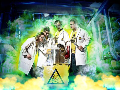 Four scientists in lab coats, surrounded by green and yellow fog, stand around a black and yellow box with a warning triangle on it