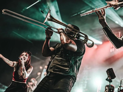 a man playing the trumpet with a female singer and a flutist either side