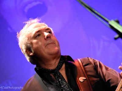 An older man looks deep in concentration as he plays his guitar