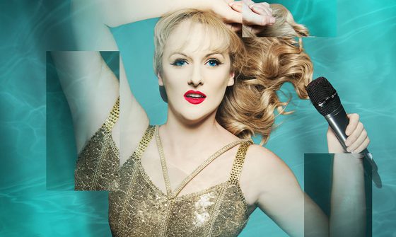 A Taylor Swift impersonator laying on a water background in a gold strappy top holding a microphone