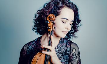 Alena Baeva with her eyes closed, holding a violin