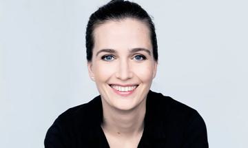 Elena Schwarz smiling at the camera on a plain light background