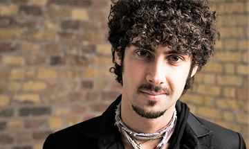 Federico Colli stood in front of a brick wall, smiling at the camera