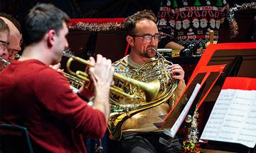 People from the Philharmonia Brass at Christmas playing musical instruments, wearing Christmas jumpers