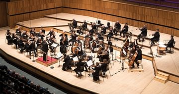 The Orchestra of the Age of Enlightenment performing on a wooden stage with musicians in formal attire, playing various instruments