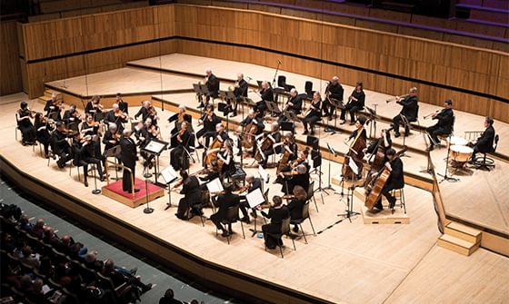 The Orchestra of the Age of Enlightenment performing on a wooden stage with musicians in formal attire, playing various instruments