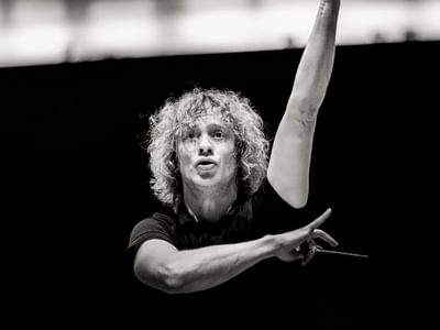 Black and white image of Santtu-Matias Rouvali passionately leading an orchestra, arms extended expressively