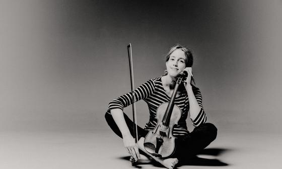 Vilde Frang cross legged on the floor holding her violin