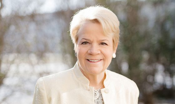 Marin Alsop, an older white woman with short light blonde hair in a snowy garden in a white blouse and jacket