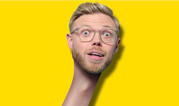 Rob Beckett's face with a long neck on a yellow background. He is wearing glasses and has a surprised expression