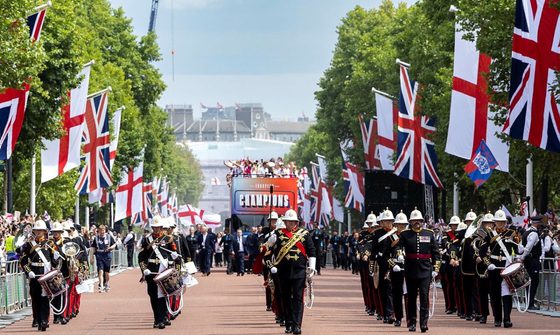 A marching band parade through London, leading the big red bus which is transporting the Lionesses