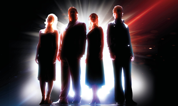 The silhouettes of two men and two women can be seen, from behind they're lit by white, red and blue light