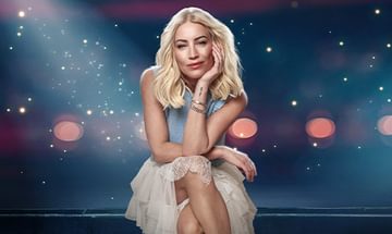 Denise Van Outen, a woman with blonde hair sitting gracefully against a sparkling, starry background wearing a light blue top and a white lace skirt